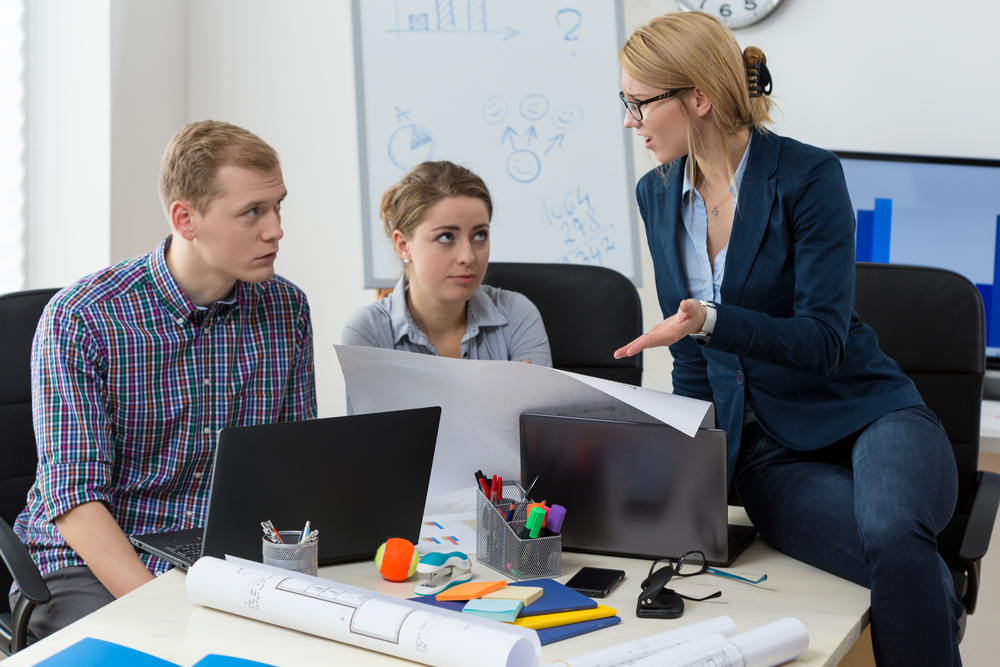 Senior sales leader coaching two junior business professionals, representing the Sales Development Representative role and B2B sales team support